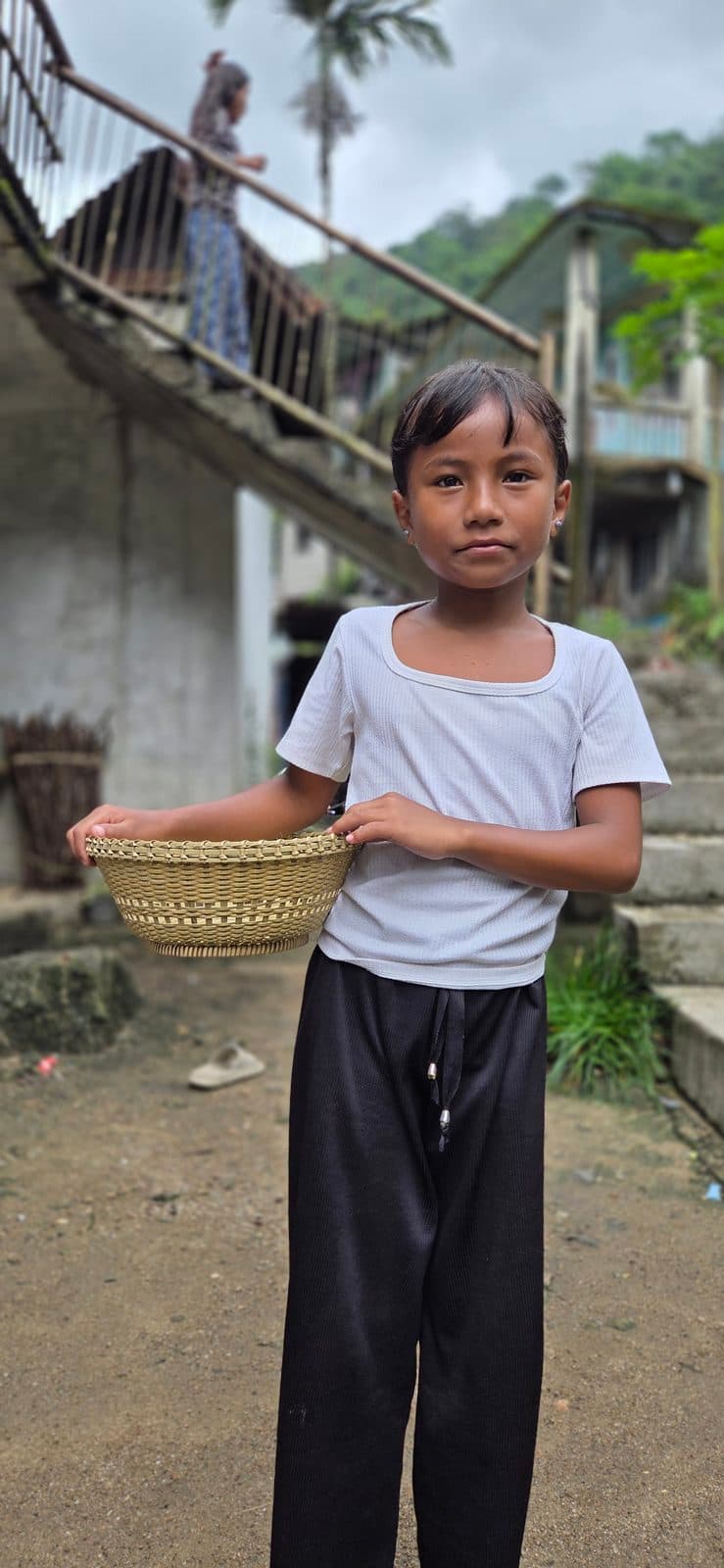 Shallow round bamboo bowl basket held in both hands, showing its size