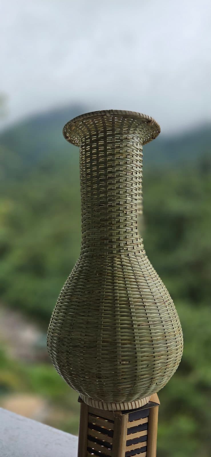 Tall handwoven bamboo vase with bulbous body and flared neck